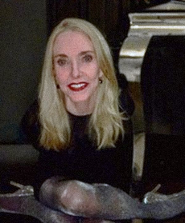 Lise smiling in red lipstick, sitting on the floor in sparkly boots.