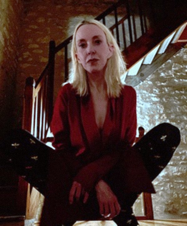 Lise crouched on an old wooden staircase in a red silk blouse.