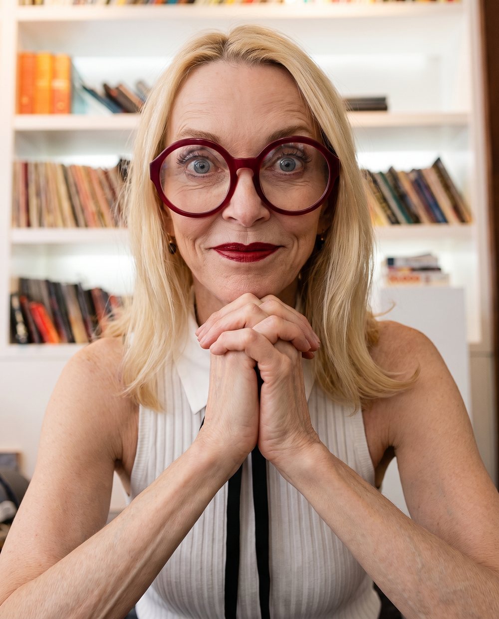 Lise Liddell in red glasses at her bookshelves.