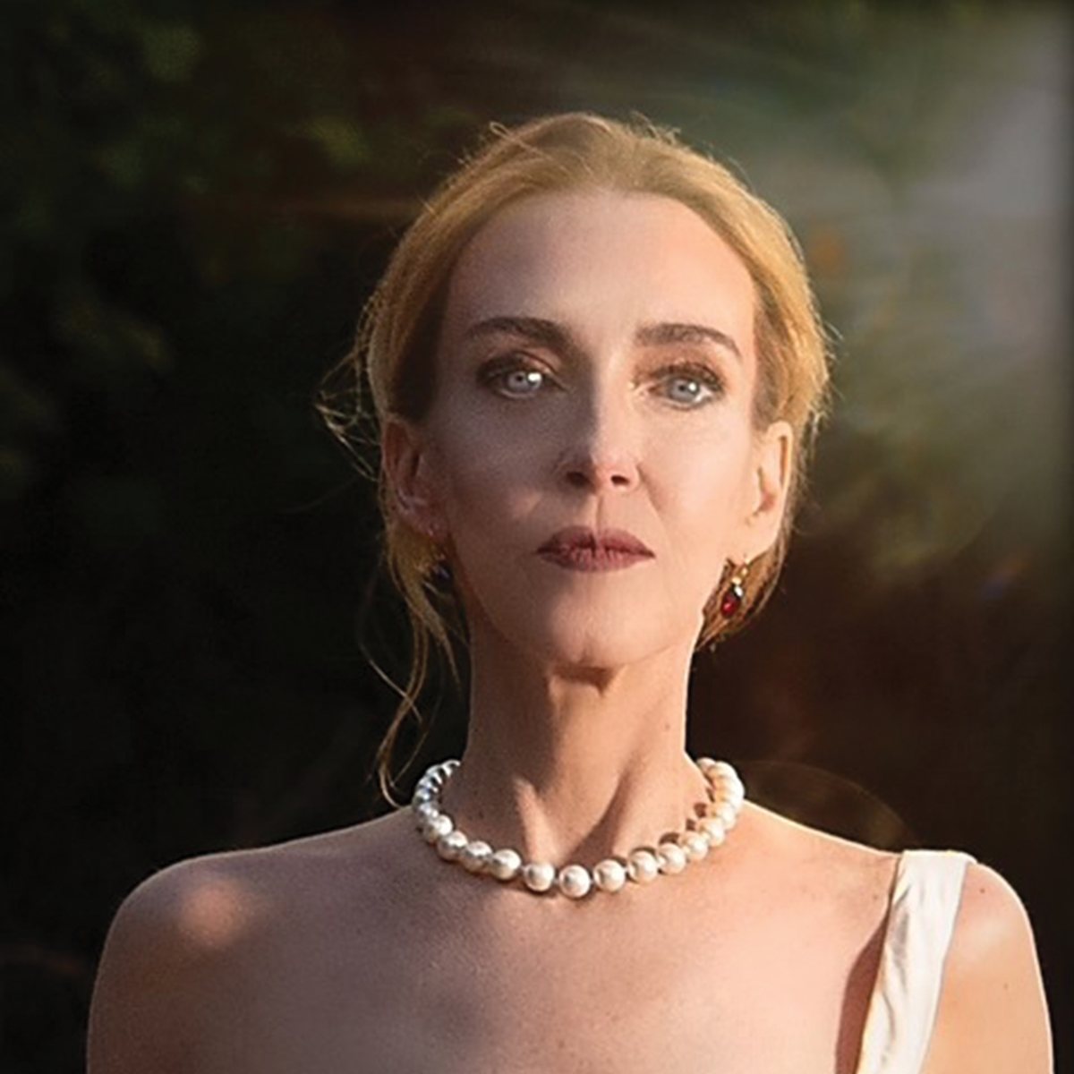 Portrait of Lise Liddell in a white gown and pearls.